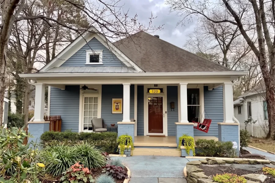 A blue Craftsman bungalow with white porch columns and a deep front porch