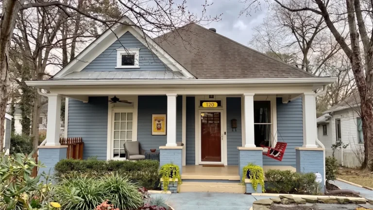 A blue Craftsman bungalow with white porch columns and a deep front porch