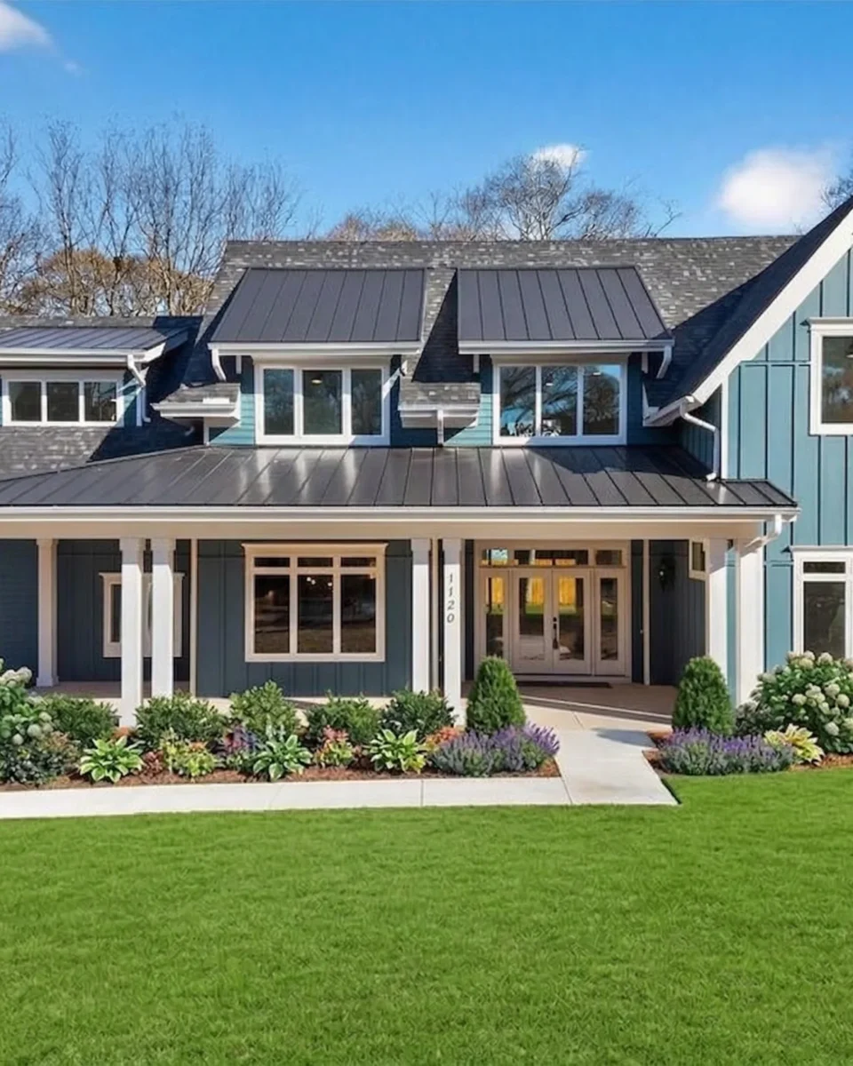 A blue and white two-story house with a deep covered porch and a standing seam metal roof