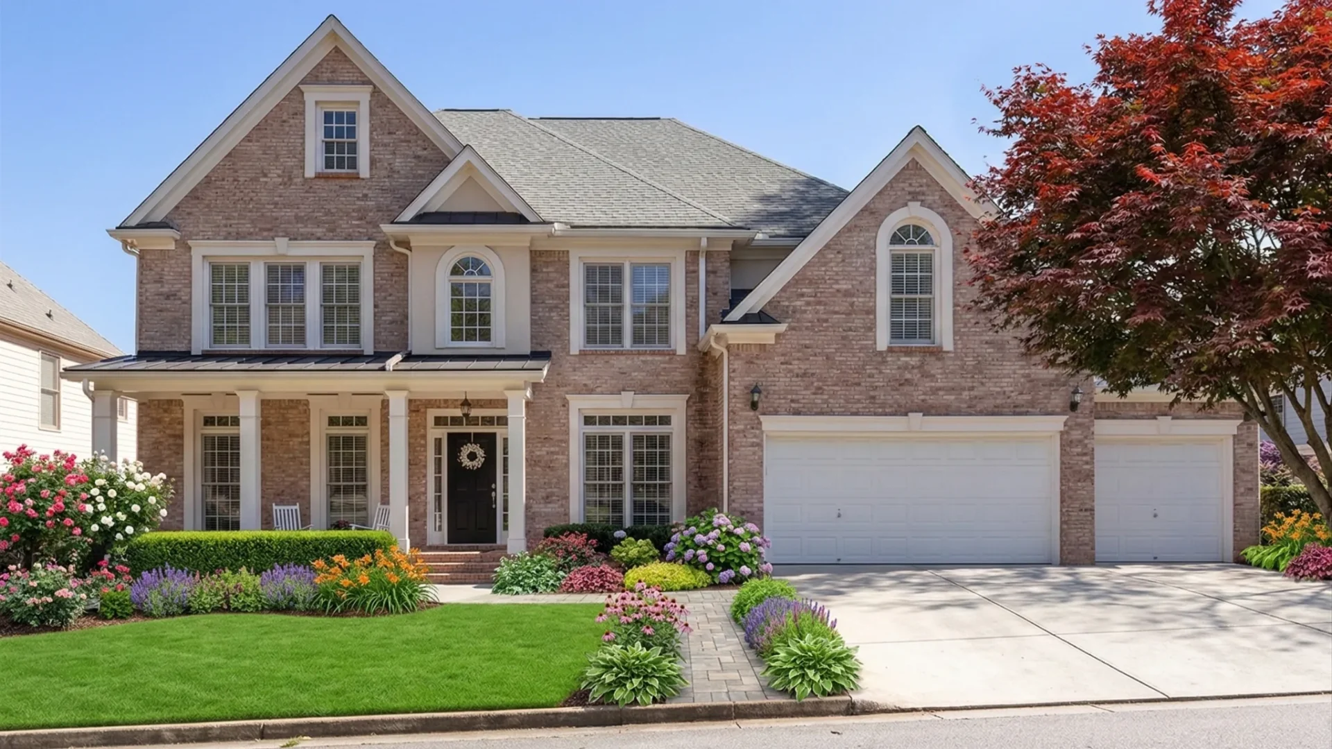 Brick and siding two-story with a three-bay garage and a red maple