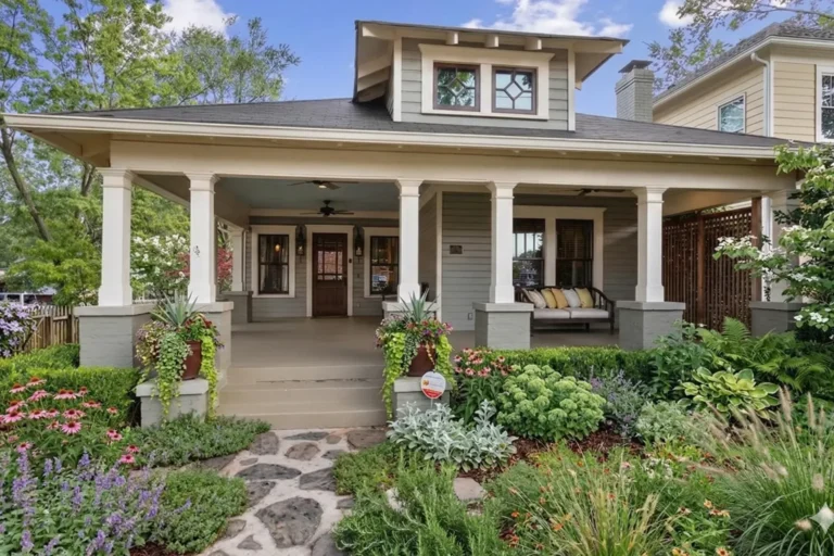 A Craftsman bungalow with tapered porch columns and a cottage garden