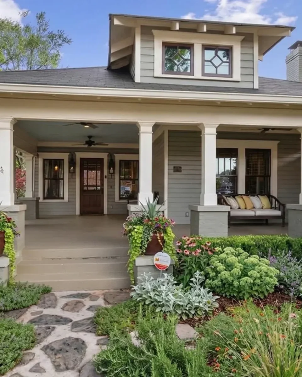 A Craftsman bungalow with tapered porch columns and a cottage garden