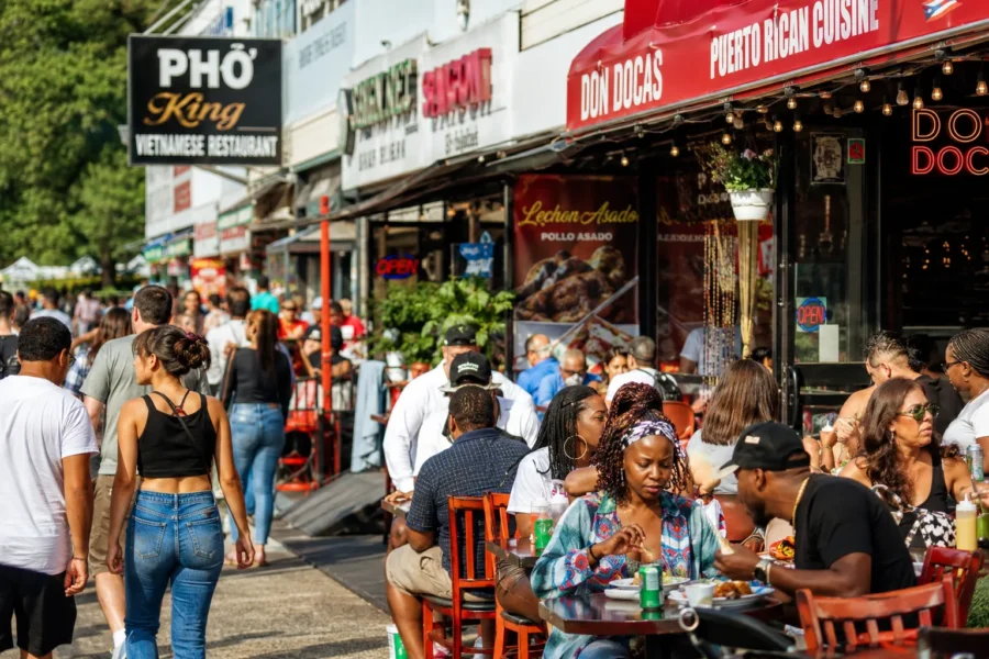 A crowded street of restaurants with people eating at outdoor tables