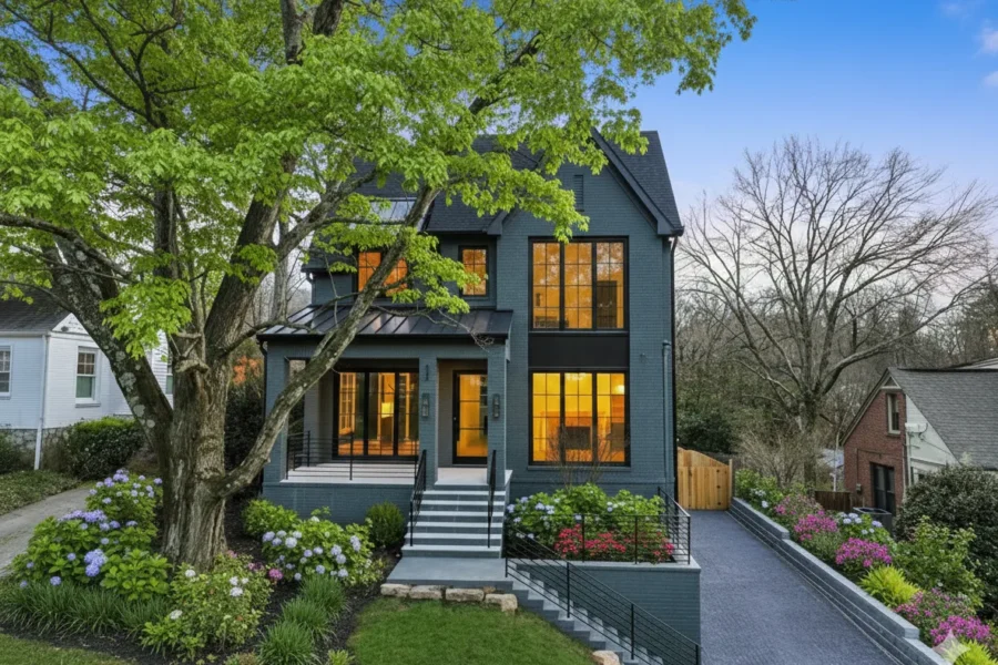 A dark modern house lit from within on a sloping site