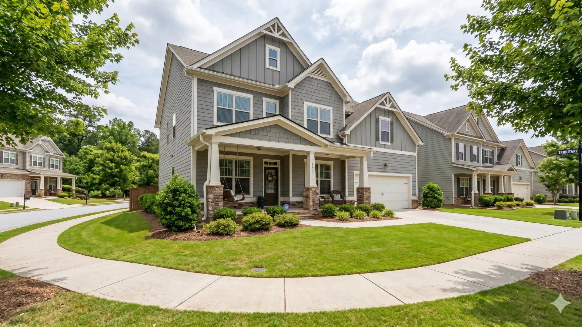 Grey craftsman two-story with a front porch and garage on a street of new homes