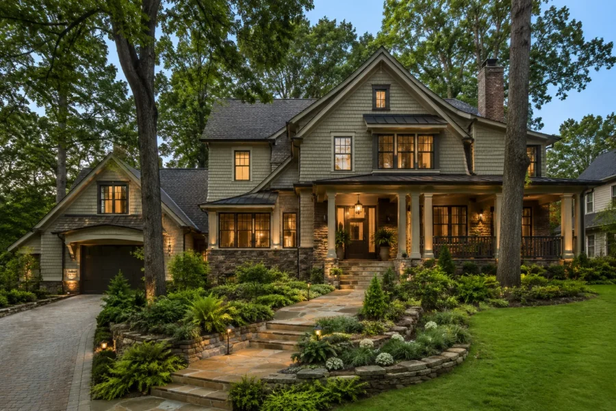 A green shingled house lit at dusk on a terraced slope