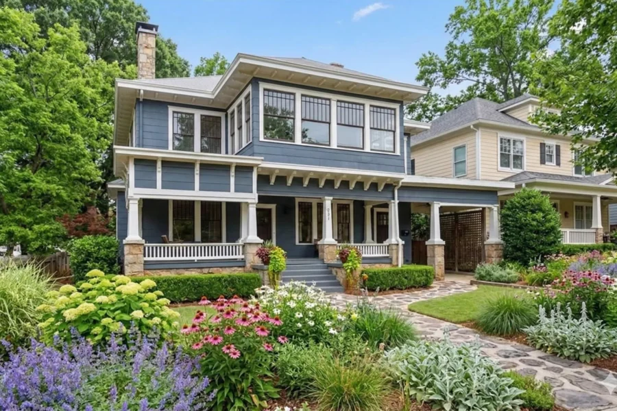 A grey house with a screened upper porch above layered front planting