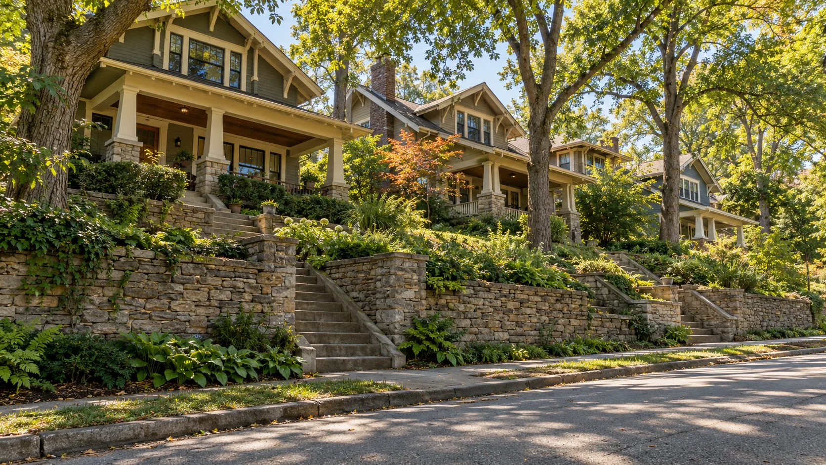 A hilly residential street where craftsman houses sit on raised lots above the roadway, with stacked stone retaining walls and steep runs of steps climbing to each front porch under mature trees
