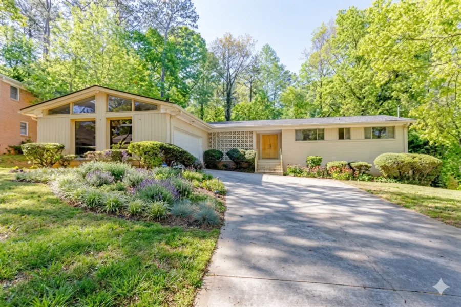 Mid-century brick ranch with a wide carport and a sloping planted drive