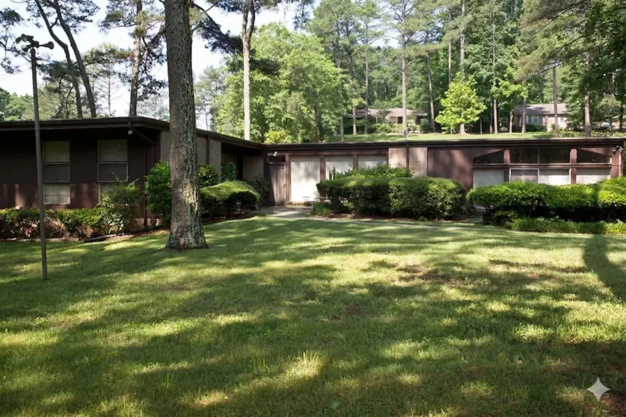 Mid-century brick ranch among mature pines with a carport and level lawn