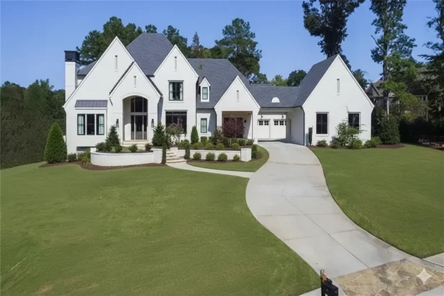 White painted-brick house with a steep slate roof and a curved drive