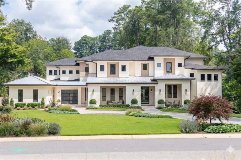 A large modern white and grey house with a low roof above a clipped lawn