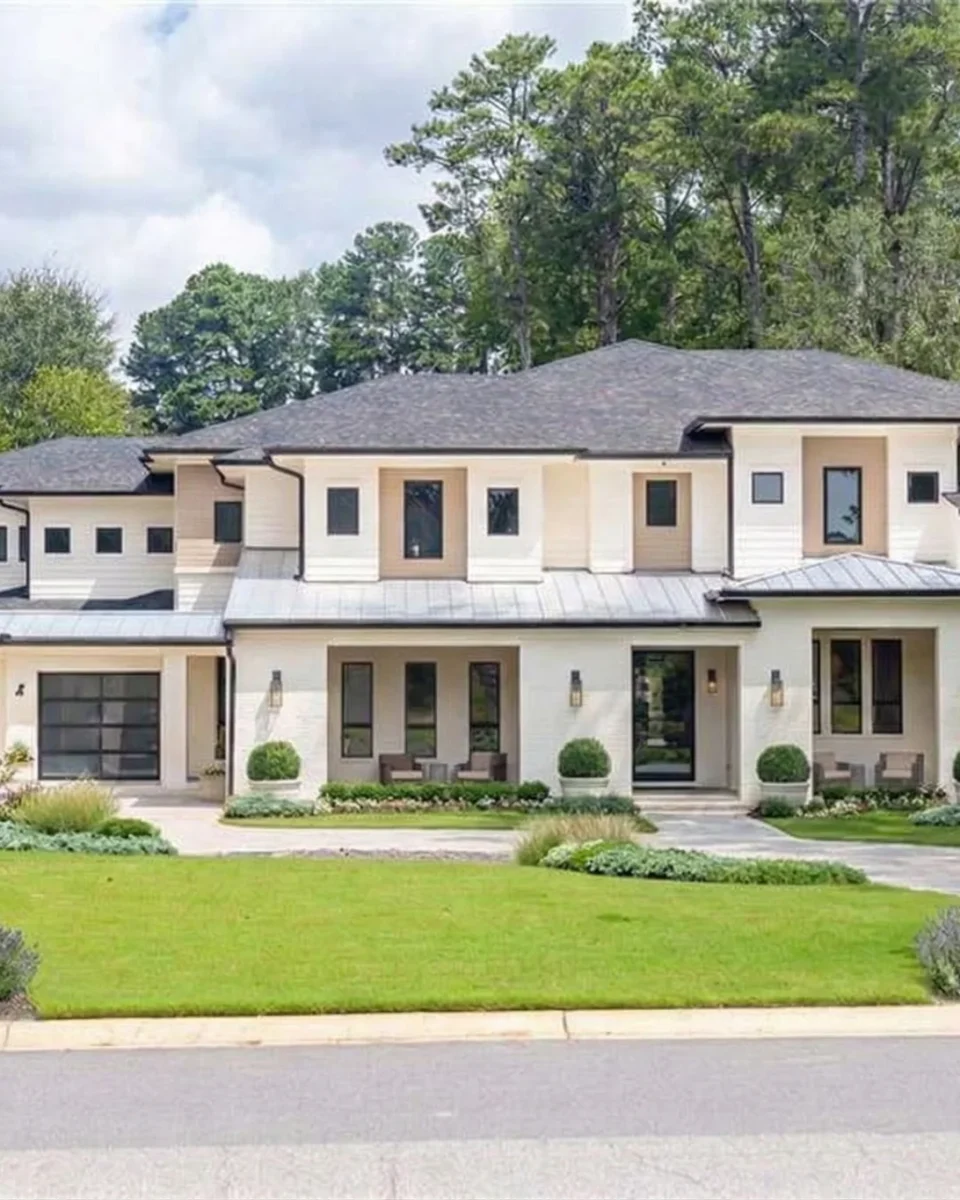 A large modern white and grey house with a low roof above a clipped lawn