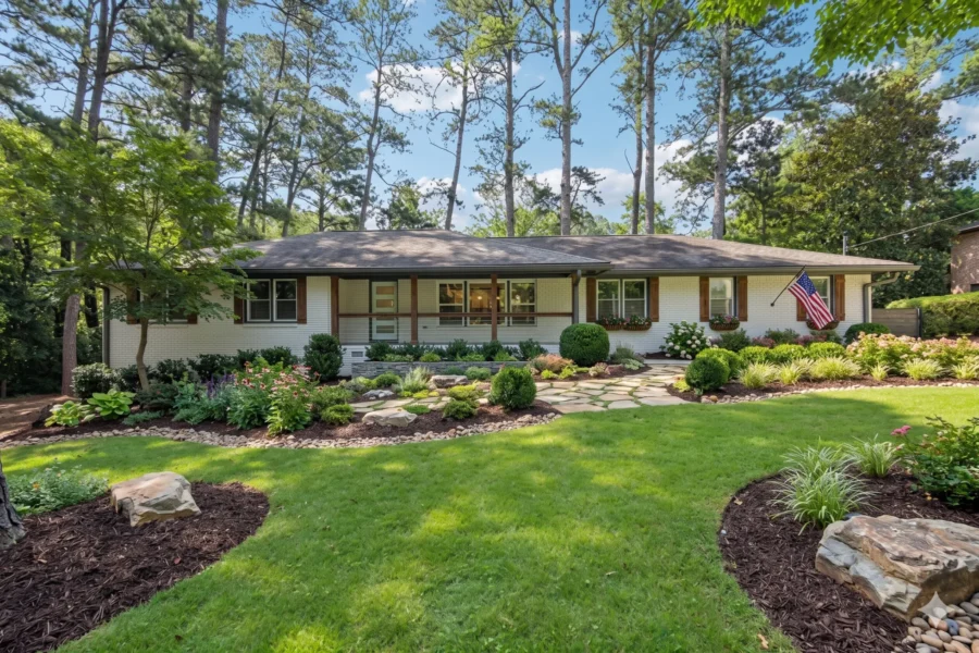 A long ranch house with a low roof behind boulder edged planting beds