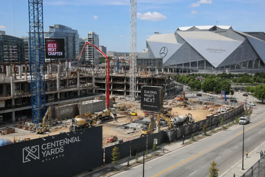A stadium district under construction with tower cranes and a new tower rising