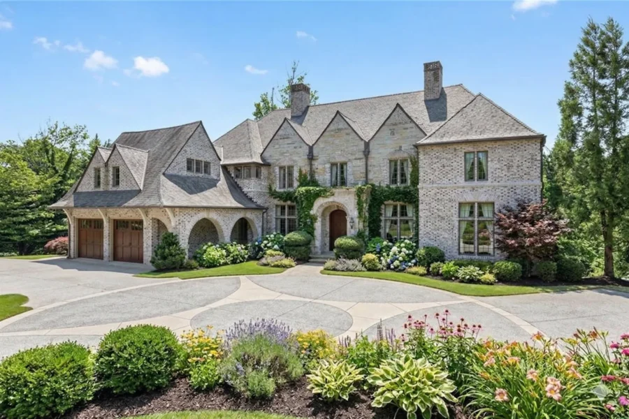 A large stone house with steep gables and a circular drive