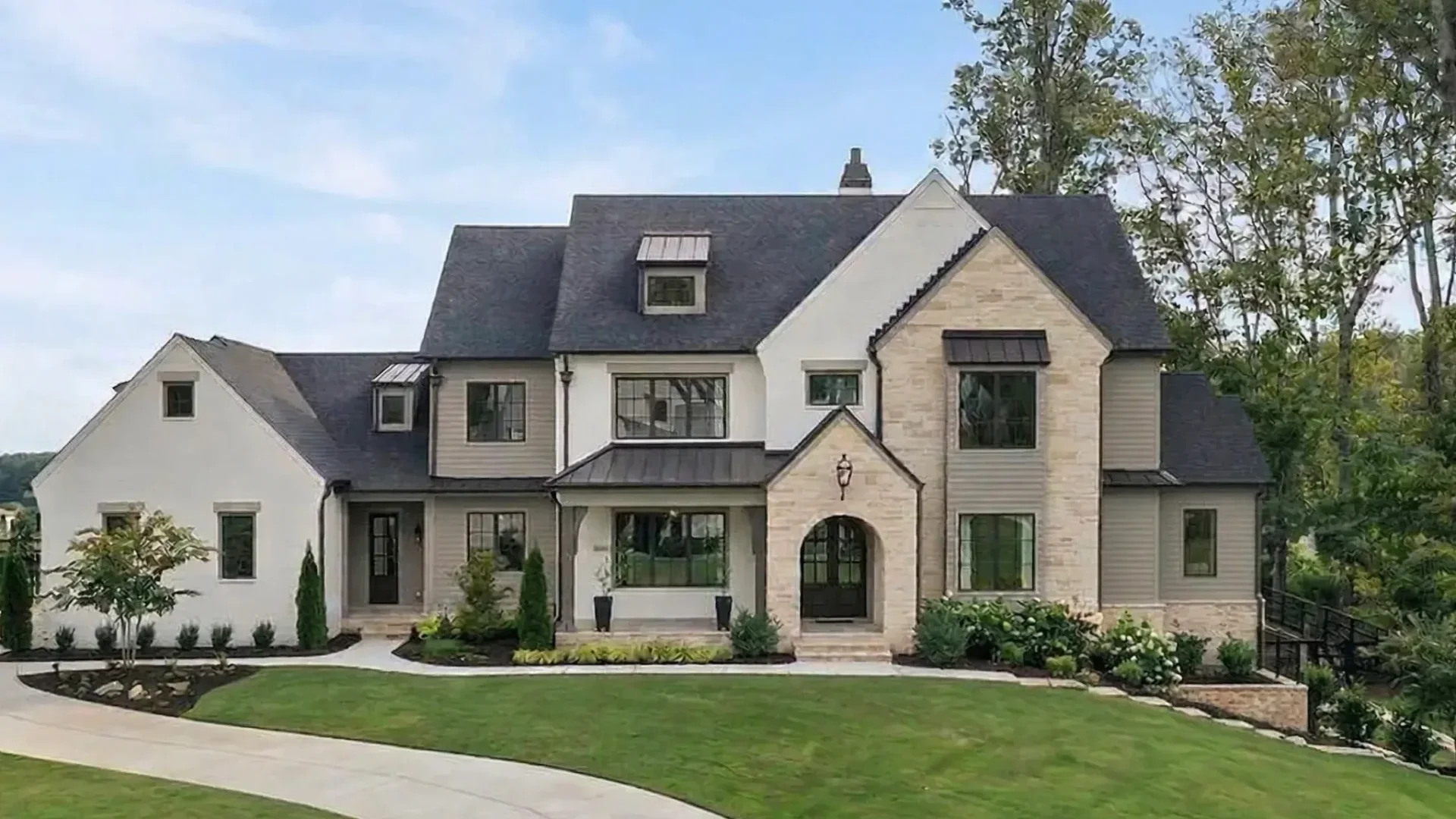 A stone and stucco house with steep gables and an arched front entry