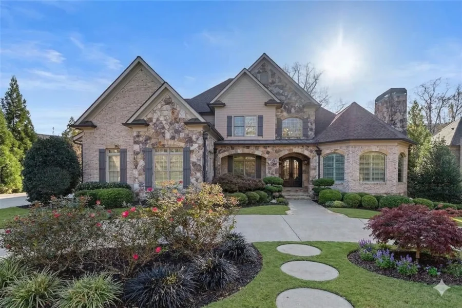 A stone and stucco house with arched windows above a stepping stone path