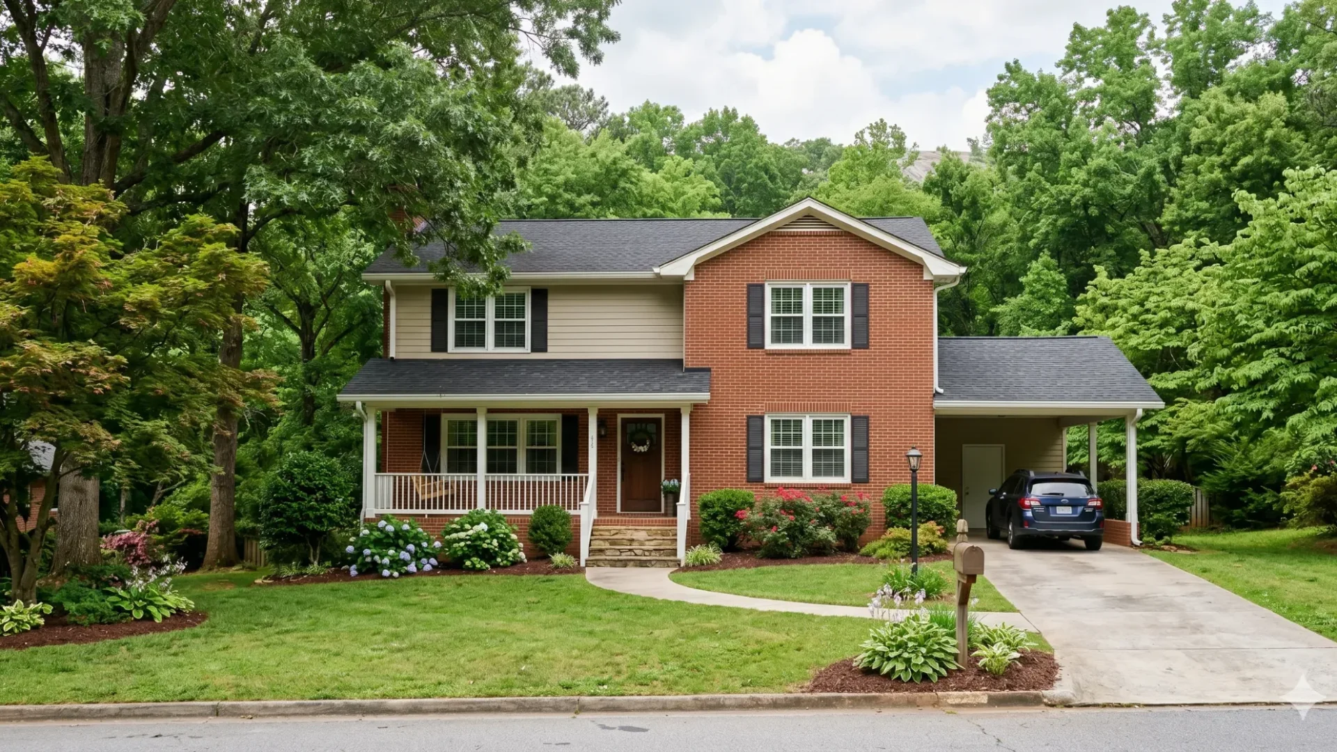A two-storey house with red siding, a front porch and a carport under trees