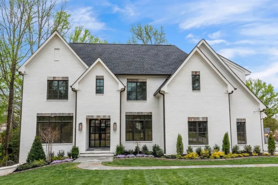 A white painted brick house with steep gables and black windows