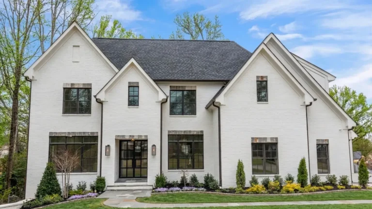 A white painted brick house with steep gables and black windows