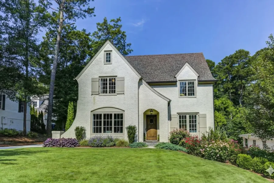 A white painted brick house with steep gables above a wide clipped lawn
