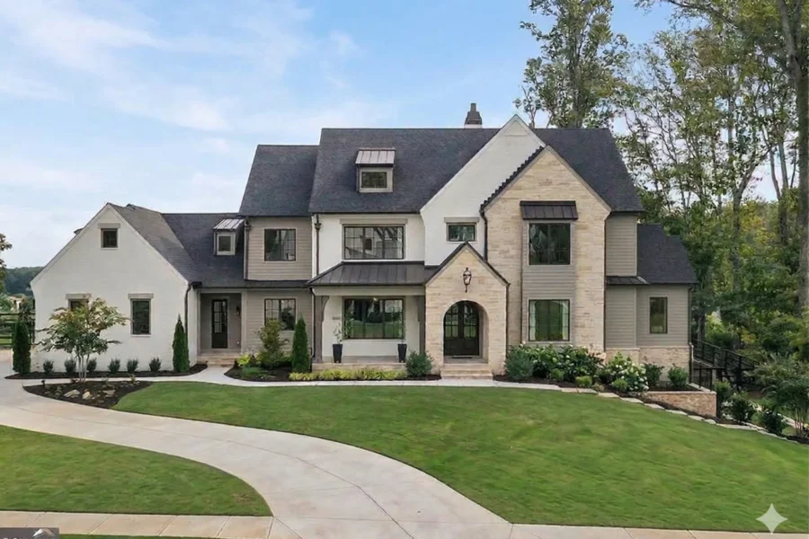 A white and stone house with steep gables and a curved drive