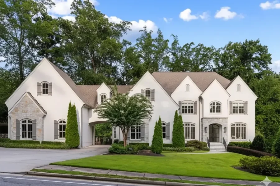 A large white stone and stucco house with steep gables and a manicured lawn