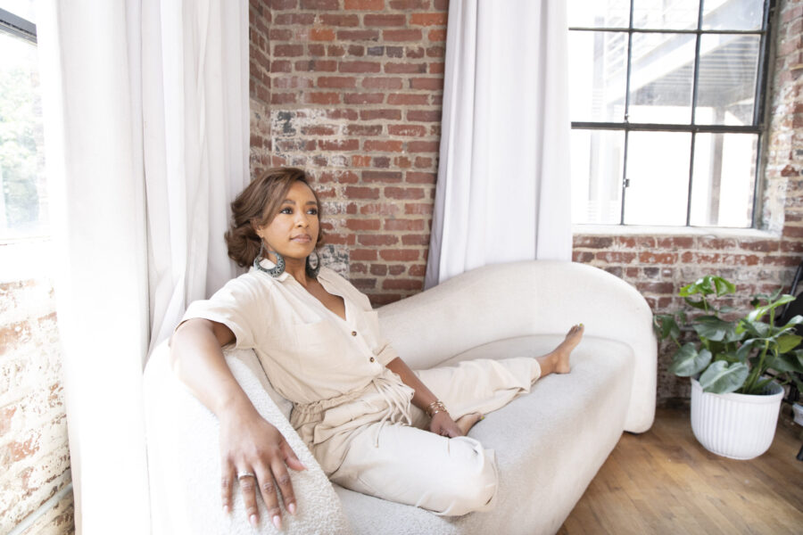 Kristen Johnson seated on a sofa beside a window in an Atlanta loft