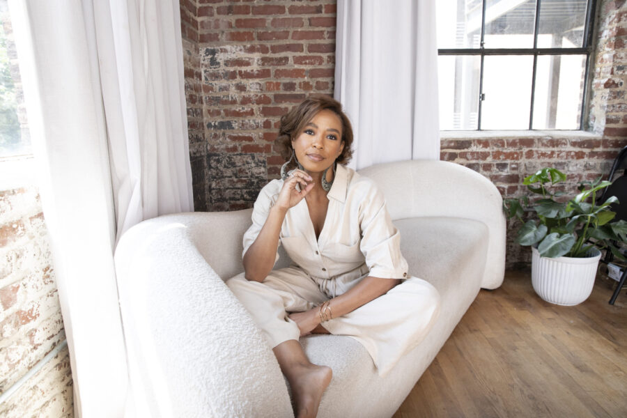 Kristen Johnson sitting cross-legged on a sofa, relaxed and smiling