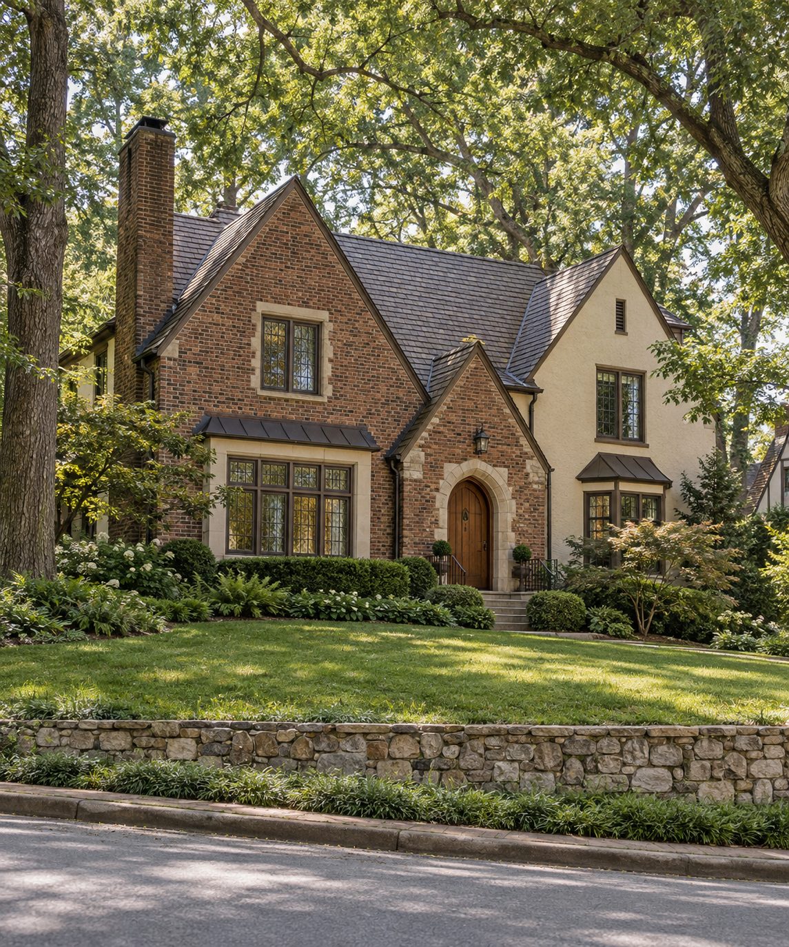 A brick and stucco Tudor revival home above a low stone wall on a shaded street in Morningside Lenox Park, Atlanta